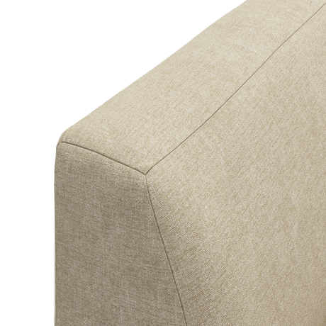 Nærbillede af beige stofbetrukket sofa-arm i studie.