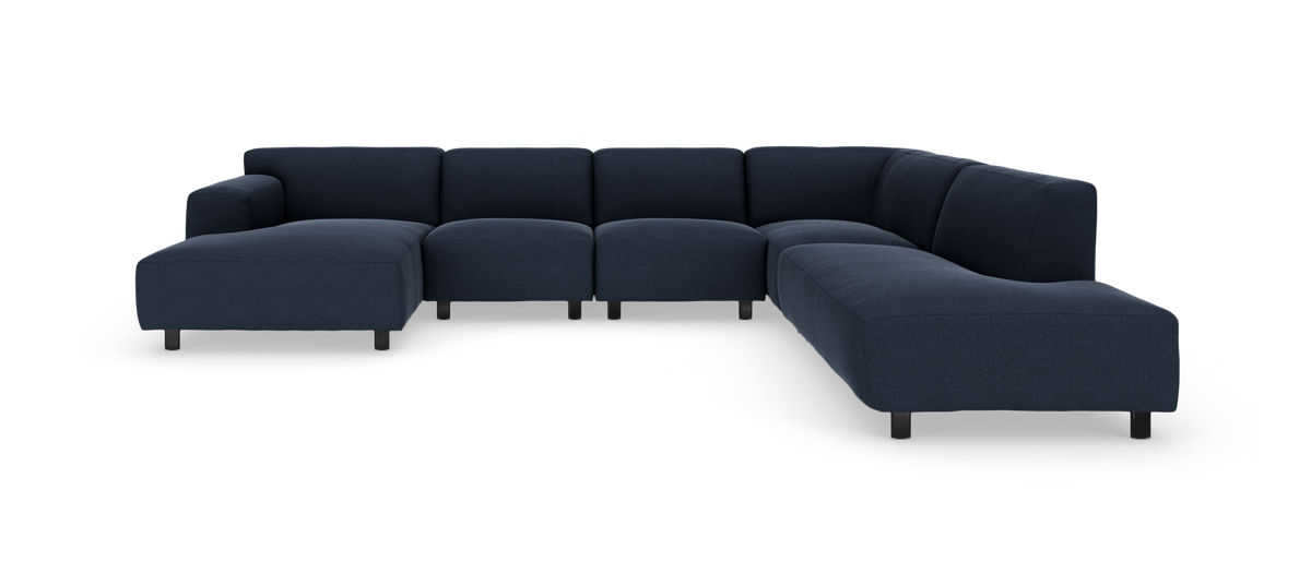 Mørkeblå modulær hjørnesofa med chaiselong til venstre, vist i studieopsætning.