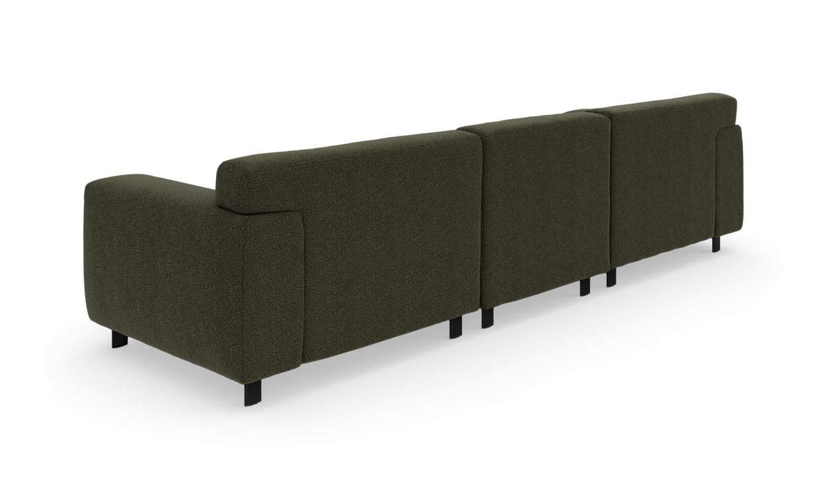 Mørkegrøn modulsofa med sorte ben set skråt bagfra på hvid baggrund.