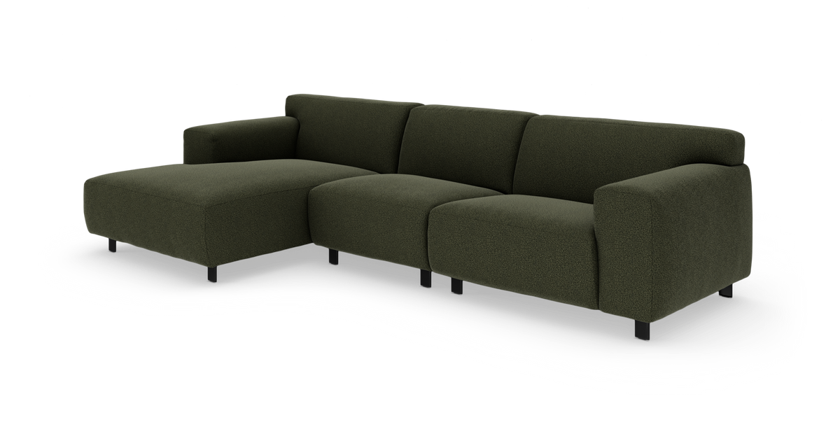 Mørkegrøn hjørnesofa med venstre chaiselong, afrundede ryg- og armlæn samt sorte ben på hvid baggrund.