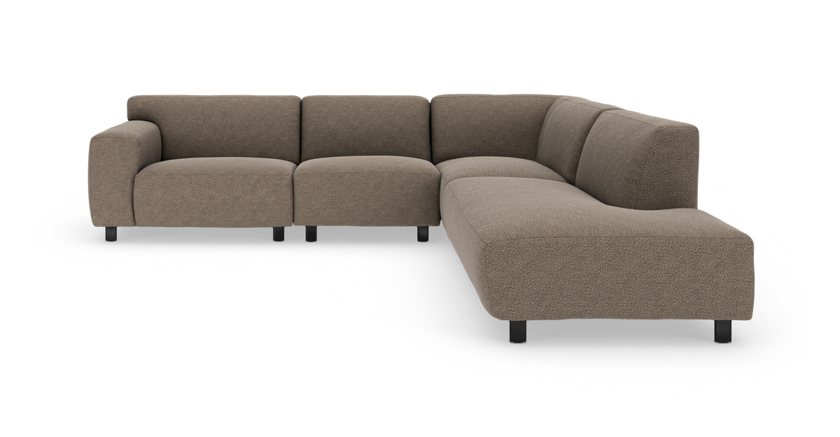 Modulær L‑sofa i brunmeleret stof med bløde, afrundede former og sorte ben, vist på hvid studiobaggrund.