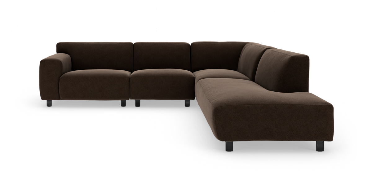 Mørkebrun L‑formet modulsofa i stof med lave metalben, fotograferet skråt forfra på hvid baggrund.