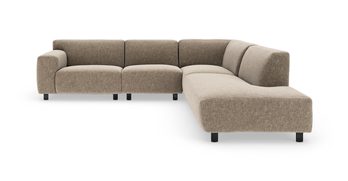 L-formet modulsofa i beige stof med lave sorte ben, vist i en frontvinklet studiebillede.