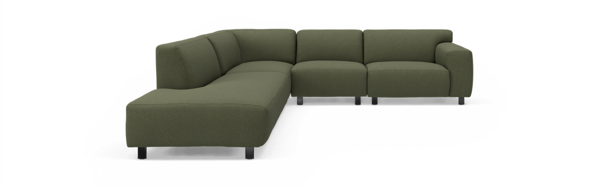 Grøn L-formet modulsofa i stof med sorte ben, fritlagt produktbillede.
