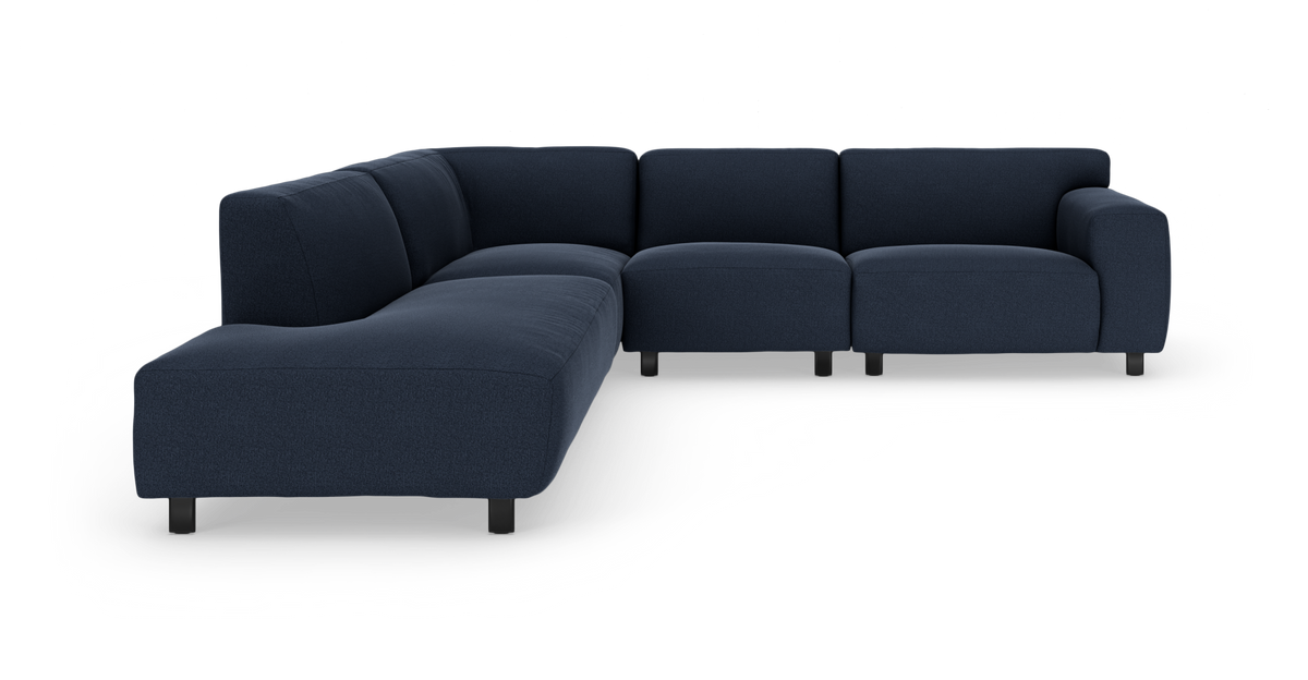 Mørkeblå modulsofa i L‑form med lave sorte ben, fritlagt på hvid baggrund.