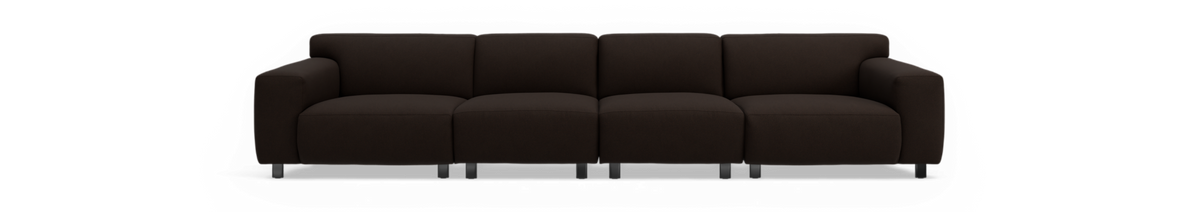 Mørkebrun 4-personers sofa med armlæn på begge sider og sorte ben, frilagt mod sort baggrund.
