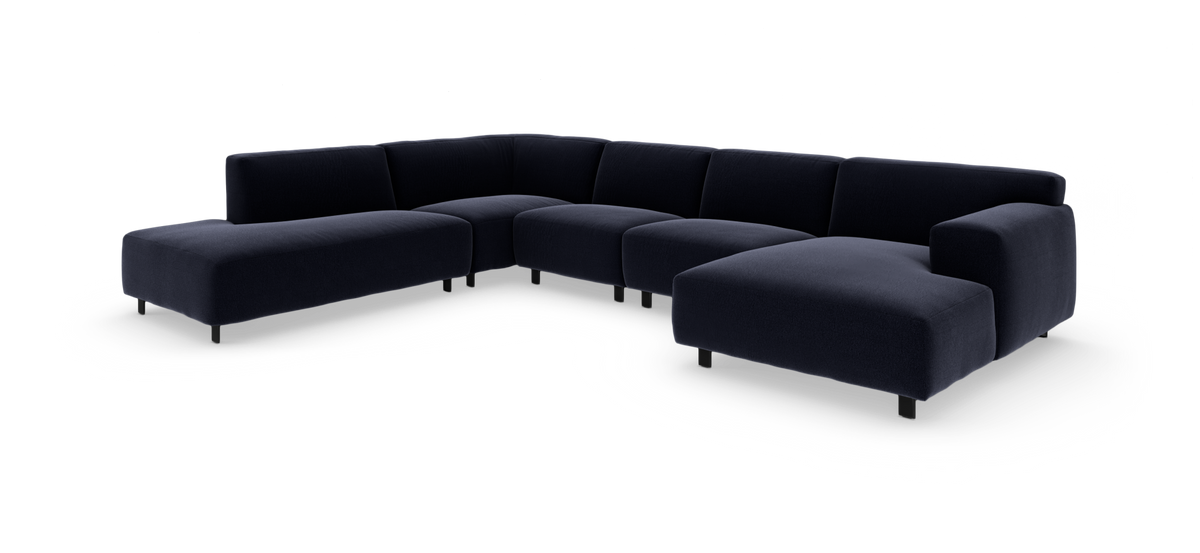 Mørkeblå modulsofa i U‑form med bred chaiselong, frilagt på hvid baggrund.