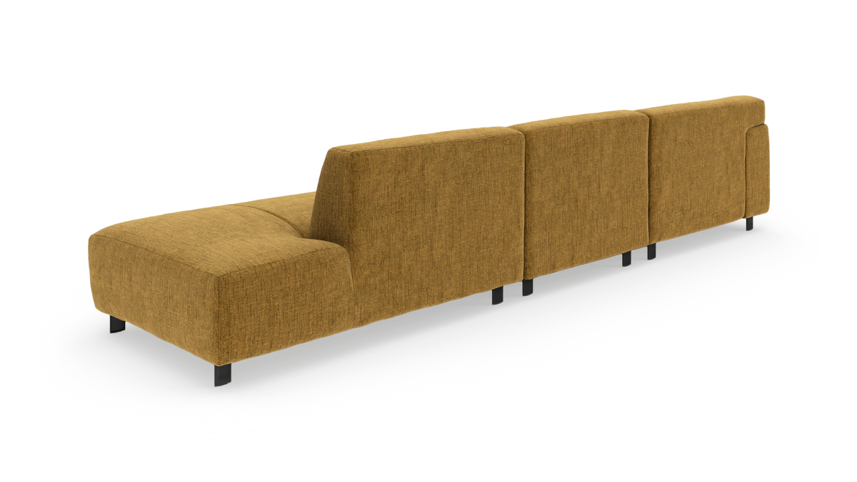 Modulsofa i sennepsgul tekstil med lav ryg og sorte ben, vist skråt bagfra på hvid baggrund.