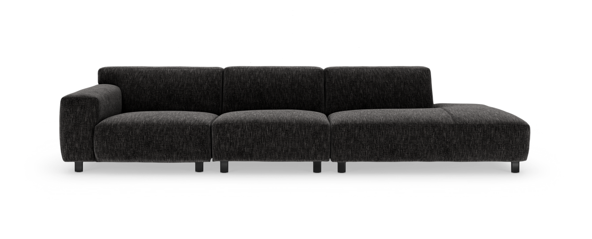 Mørkegrå modulsofa i tekstil med venstre armlæn og chaiselong til højre, fritlagt på hvid baggrund.