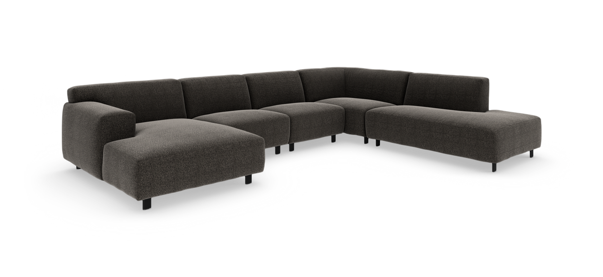 Mørkegrå L-formet modulsofa med lav ryg og slanke sorte ben, frilagt på hvid baggrund.