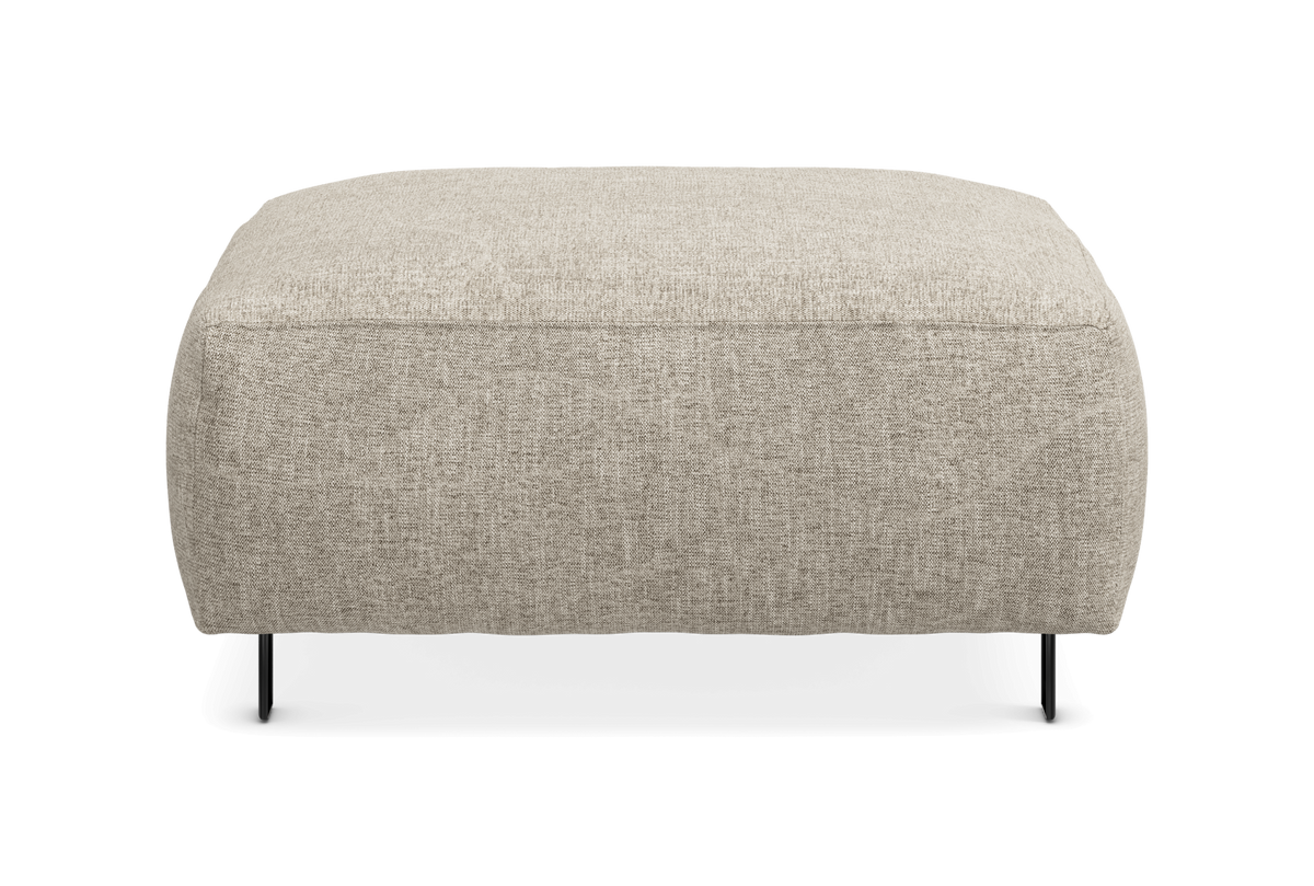 Beige polstret puf/ottoman i tekstil med slanke sorte ben, set forfra på hvid baggrund.