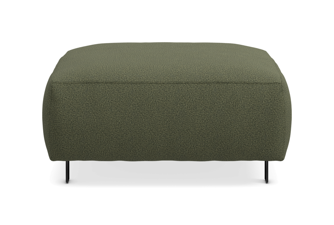 Grøn rektangulær puf/fodskammel i tekstil med slanke sorte ben, set forfra mod hvid baggrund.
