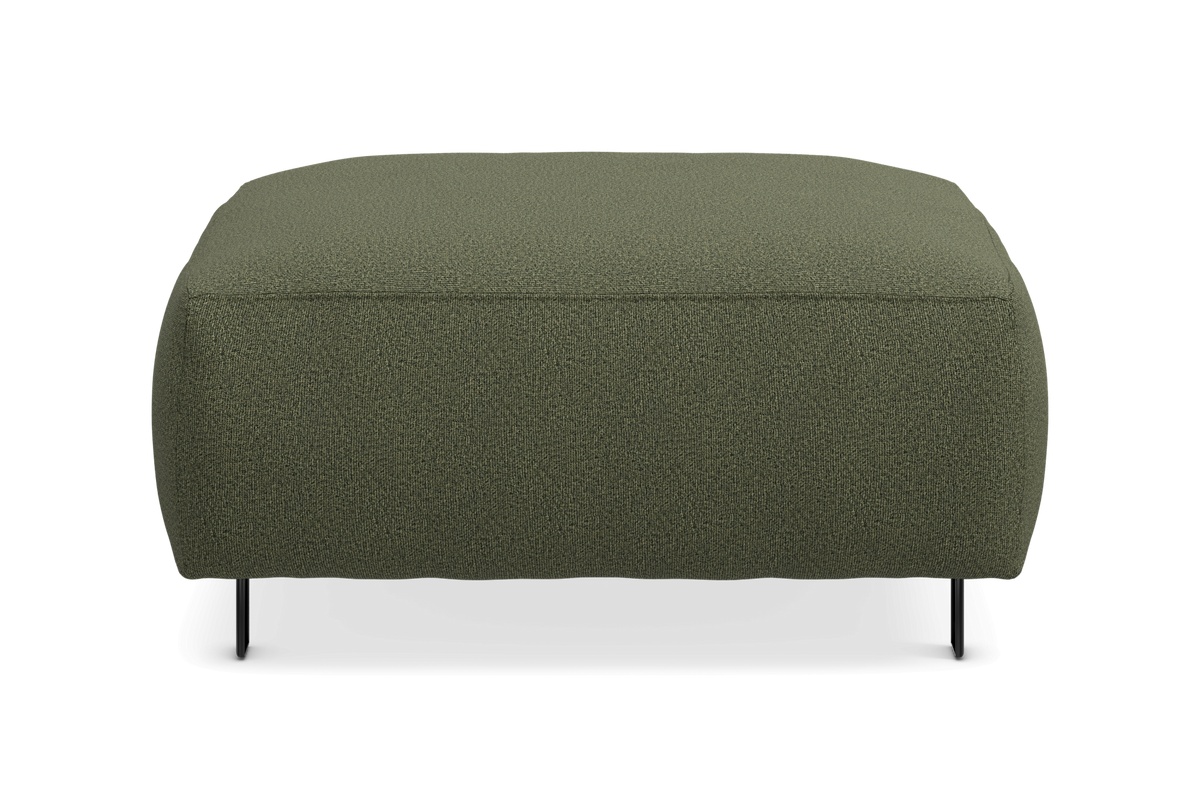 Grøn rektangulær puf/fodskammel i tekstil med slanke sorte ben, set forfra mod hvid baggrund.