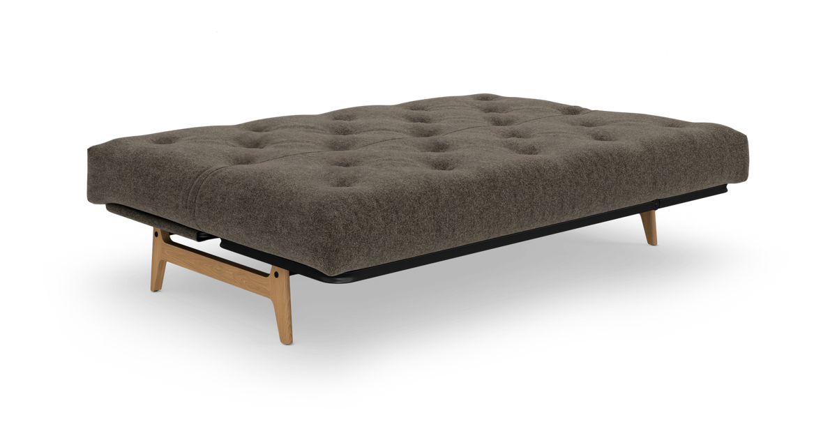 Brungrå sovesofa med tuftet madras og træben, frilagt på hvid baggrund.