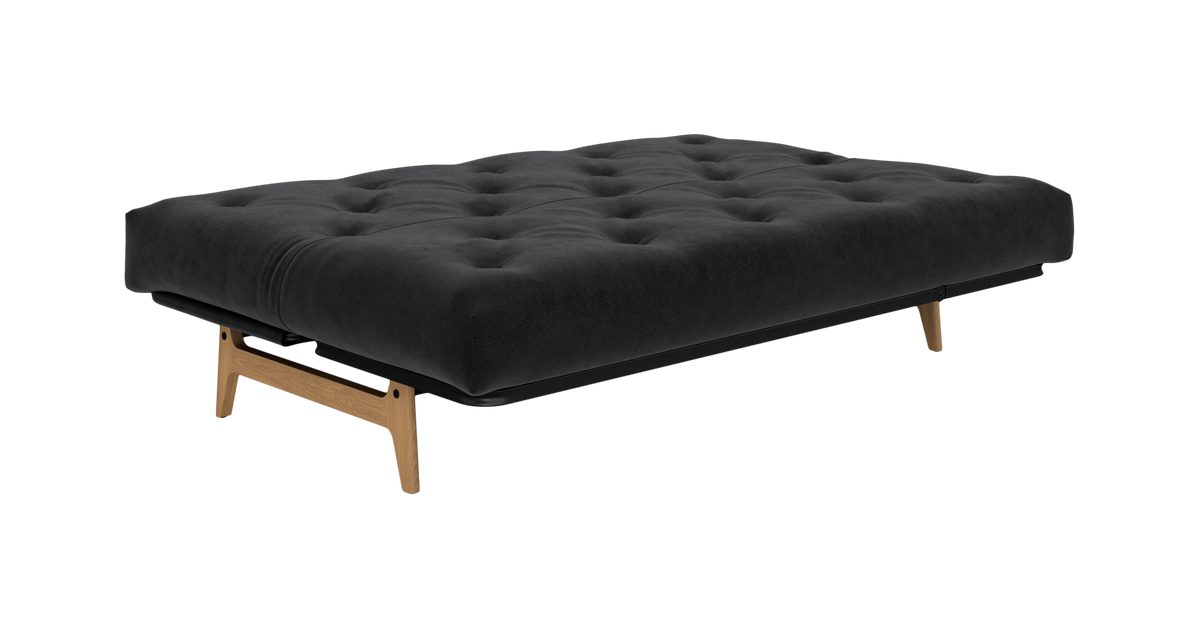 Mørkegrå tuftet sovesofa på træben, frilagt produktbillede.