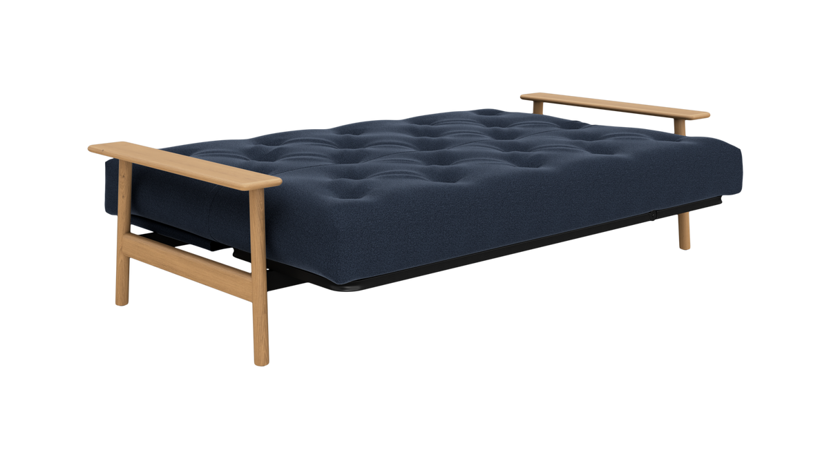 Mørkeblå sovesofa/futon med træarmlæn, set skråt forfra på hvid baggrund.