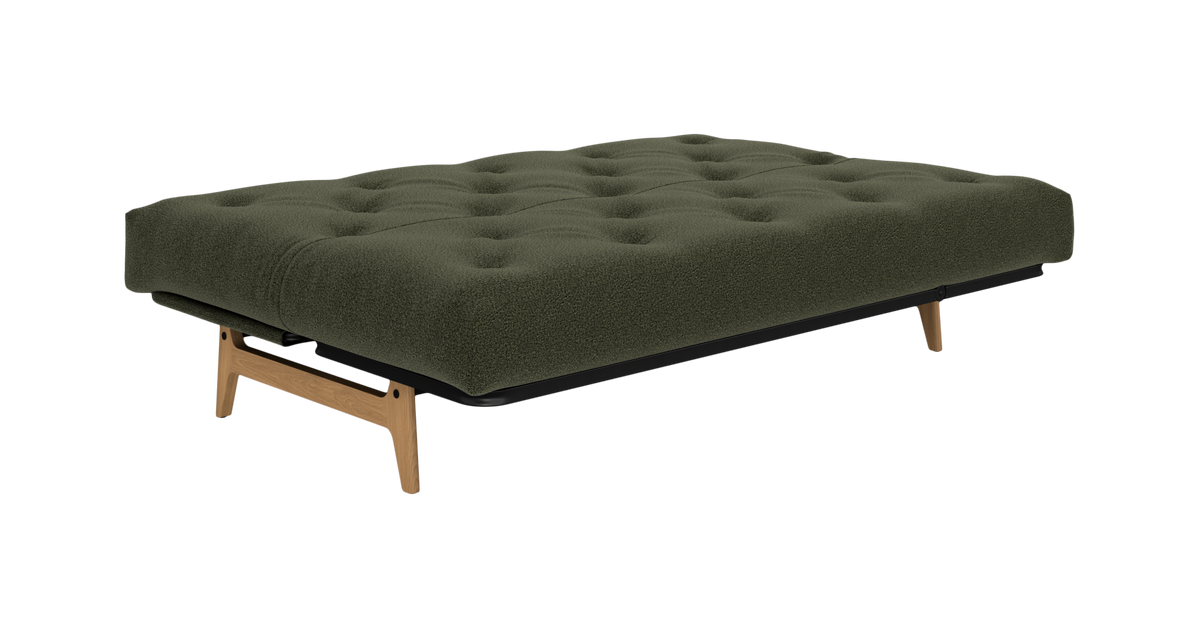 Grøn tuftet sovesofa/futon med bouclé-betræk og træben, fritlagt på hvid baggrund.