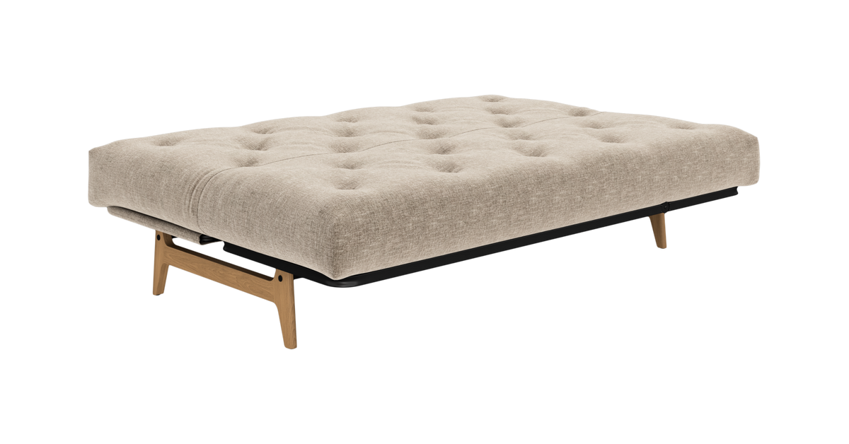 Beige sovesofa/daybed med knapstukket madras og træben, frilagt mod hvid baggrund.