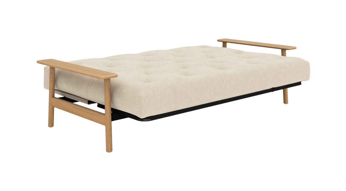 Beige, tuftet sovesofa med lyse træarmlæn og ben, frilagt på hvid baggrund.
