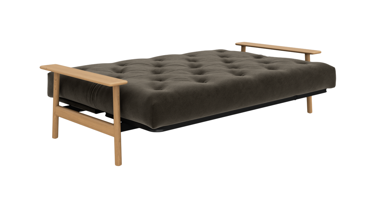 Mørkegrå, tuftet futon/sofabed med lyse træarmlæn, fotograferet skråt forfra på neutral baggrund.