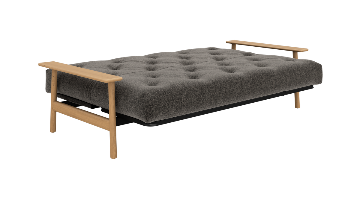 Grå sovesofa med tuftet madras og armlæn i træ, frilagt produktfoto.