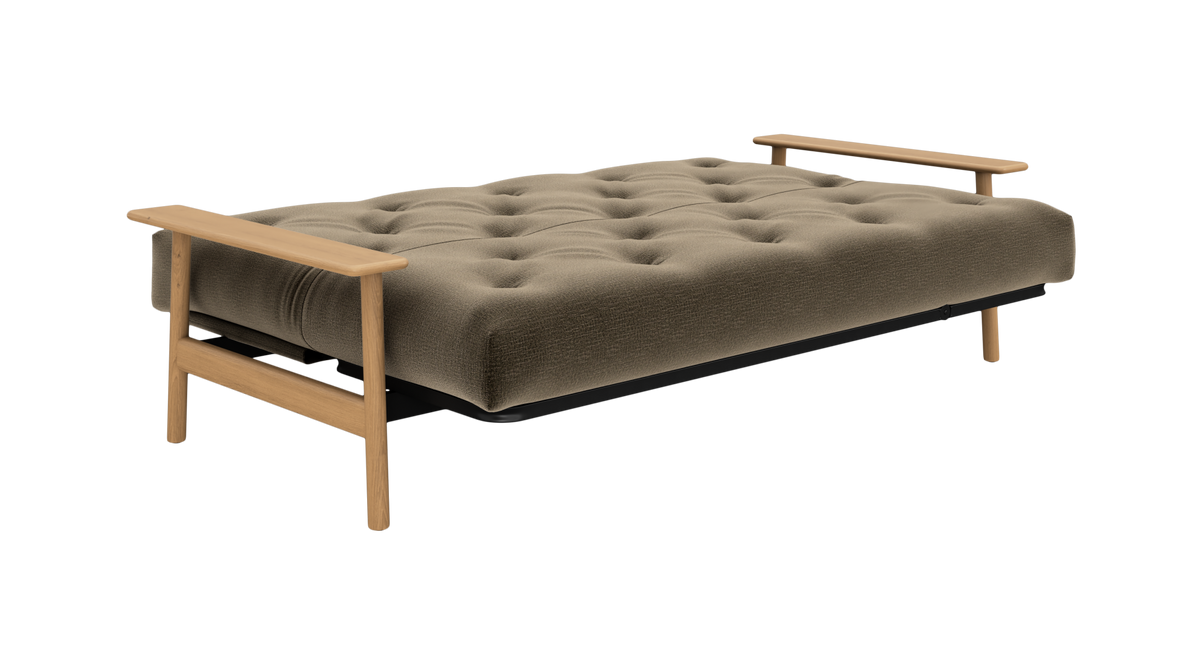 Futon sovesofa med tuftet olivgrøn madras og lyse træarmlæn, set skråt forfra på fritlagt hvid baggrund.