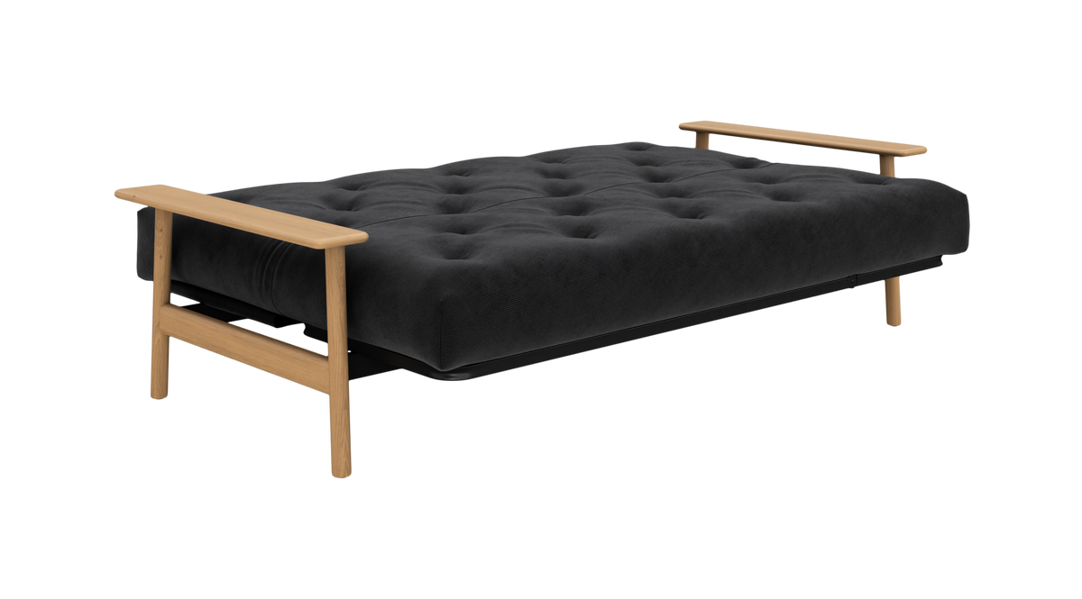 Sovesofa slået ud til seng med sort, dybtuftet madras og lyse træarmlæn og ben, frilagt produktfoto.