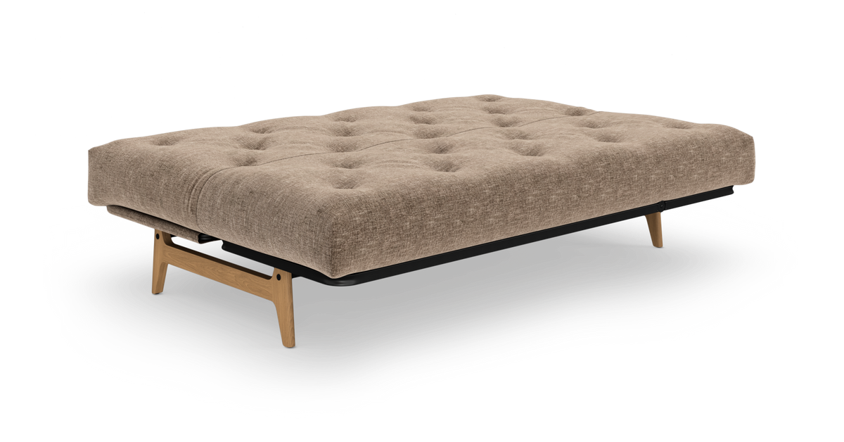 Beige, knapstukket sovesofa i udslået position med træben, set i frontvinkel mod hvid baggrund.