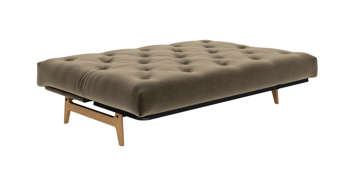Lav, tuftet daybed/futon i beige stof med træben, fotograferet skråt forfra på hvid baggrund.