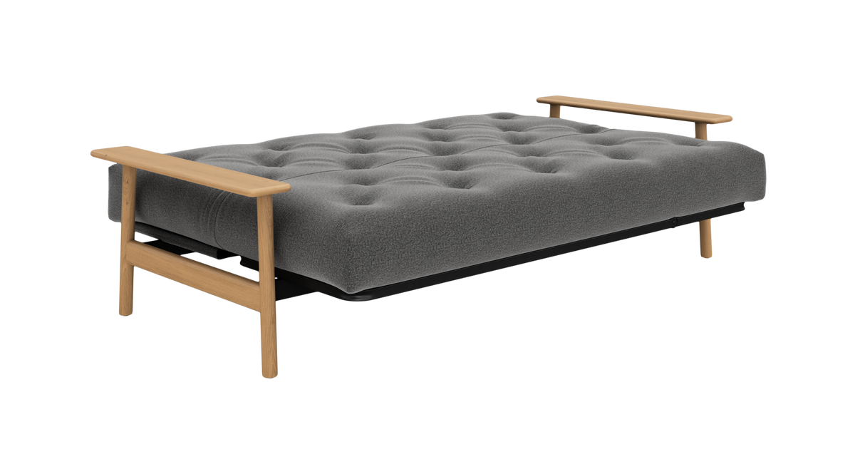 Grå, tuftet sovesofa med træarmlæn, fotograferet i studie.