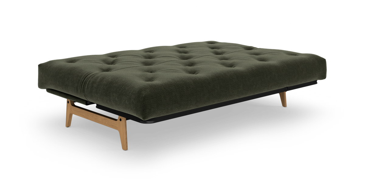 Mørkegrøn tufted futon med træben og sort ramme, frilagt på hvid baggrund i front skrå vinkel.