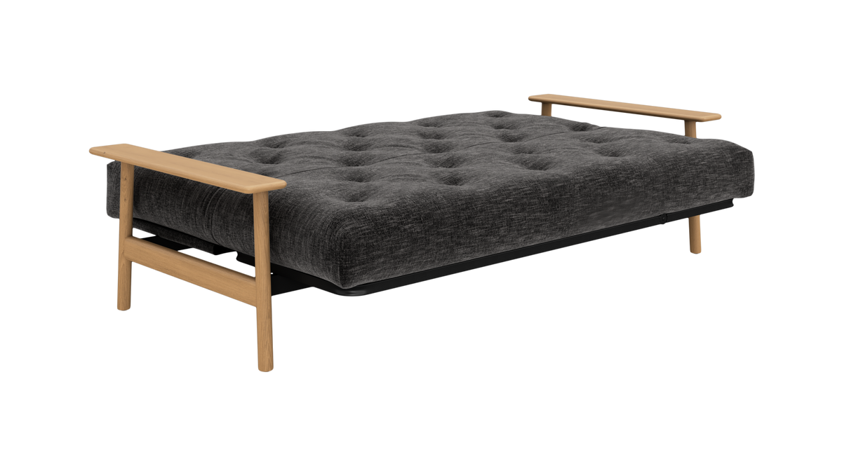 Grå sovesofa/futon i udslået position med tuftet madras og lyse træarmlæn.