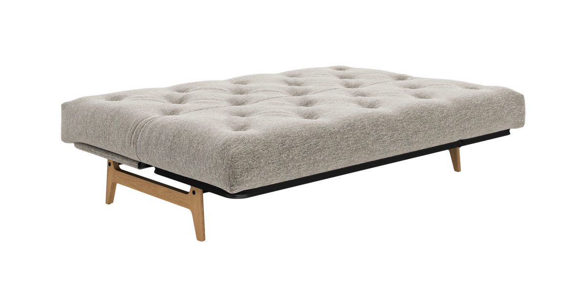 Beige daybed med tuftet madras og træben, frilagt produktfoto.