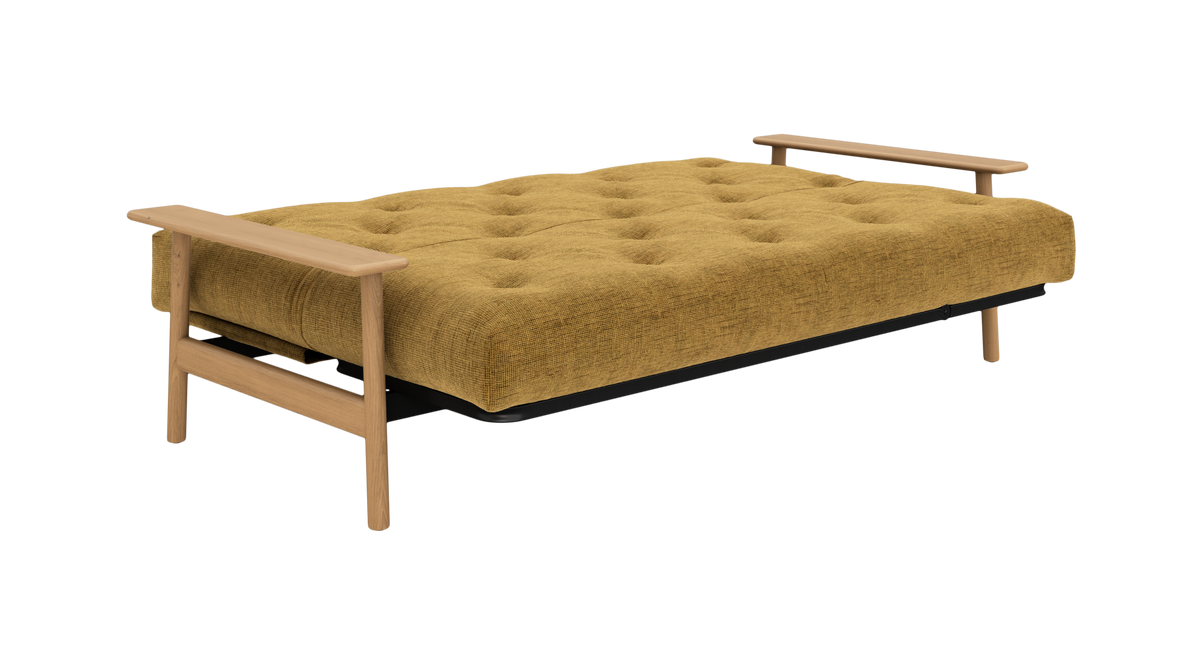 Mustardgul sovesofa/futon i udslået position med tuftet madras og træarmstøtter.