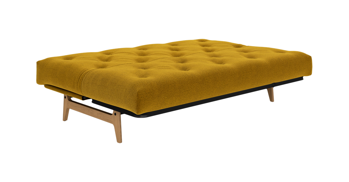 Sennepsgul tufted sovesofa/futon med træben, fritlagt produktbillede.