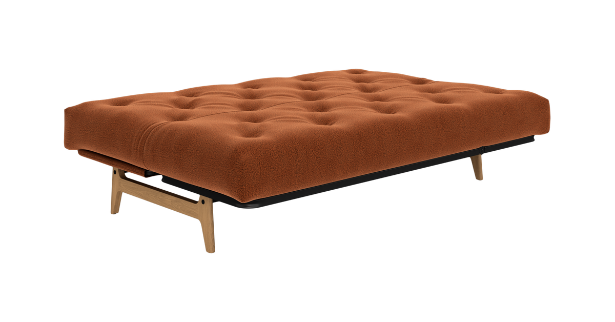 Tuftet orange polstret sovesofa/dagbænk med træben på studiebaggrund.