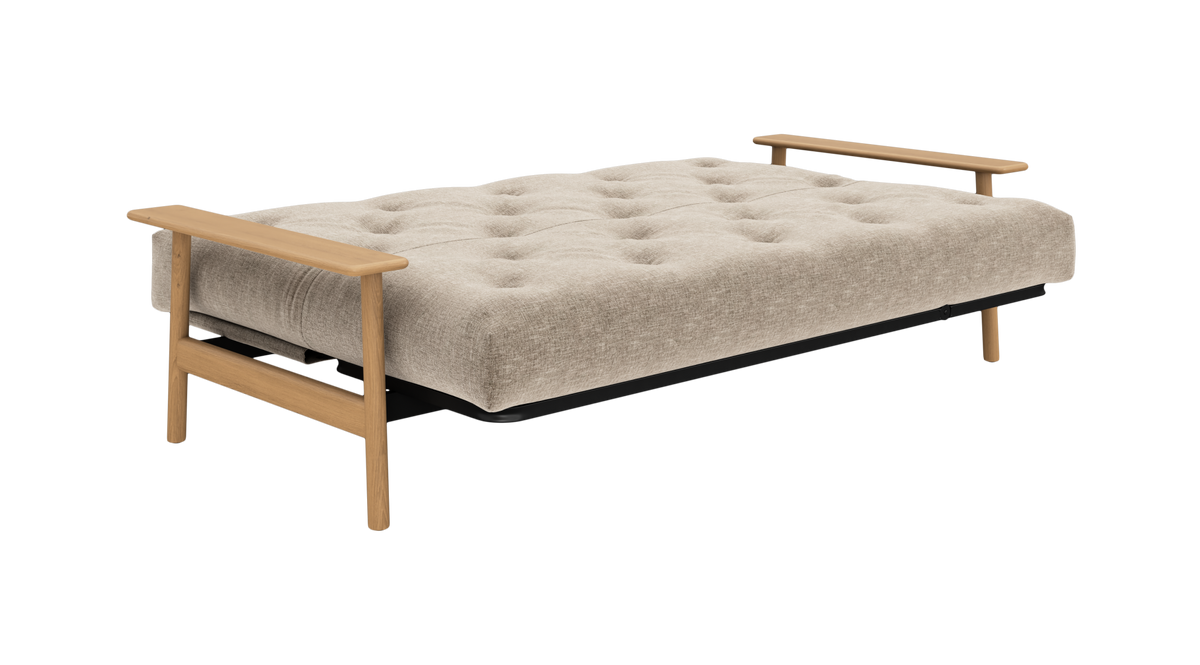Beige, tuftet sovesofa med lyse træ-armlæn og ben, frilagt i skrå frontvinkel.