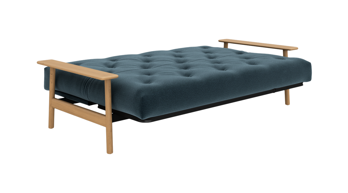 Blå, tufted sovesofa med armlæn i træ, frilagt på hvid baggrund.