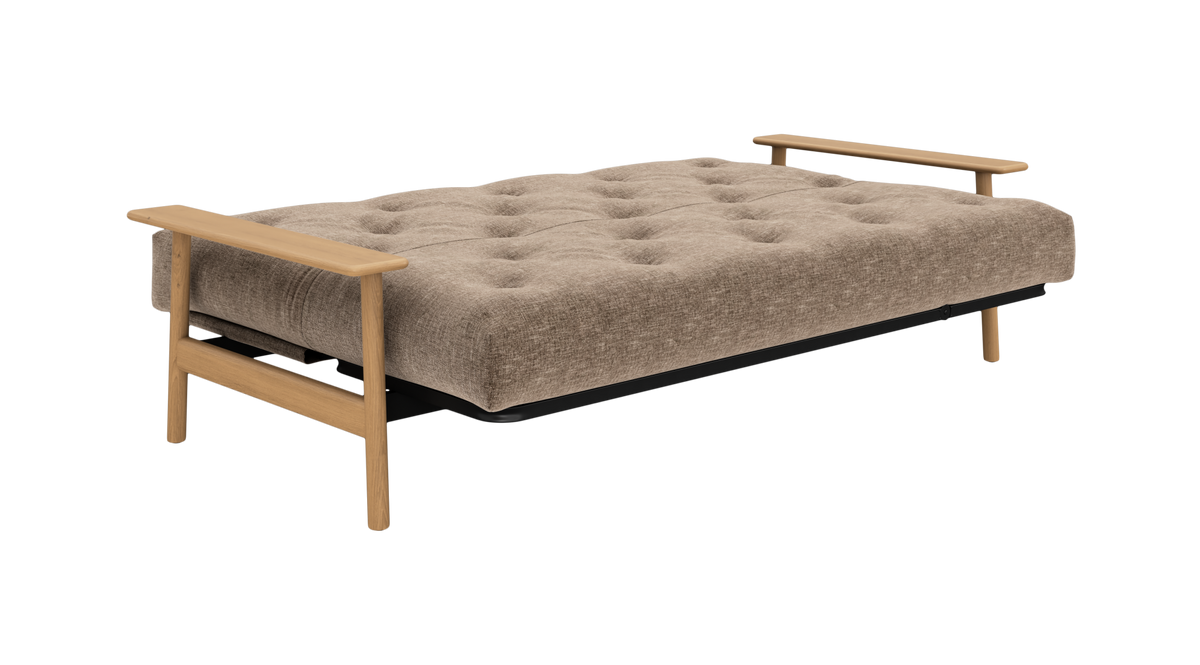 Beige sovesofa i udslået position med tuftet madras og lyse træarmlæn, frilagt på hvid baggrund.