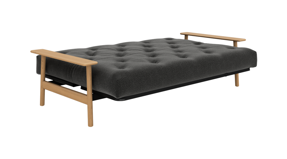 Mørkegrå tuftet sovesofa/futon med lyse træ-armlæn, fritlagt mod hvid baggrund.