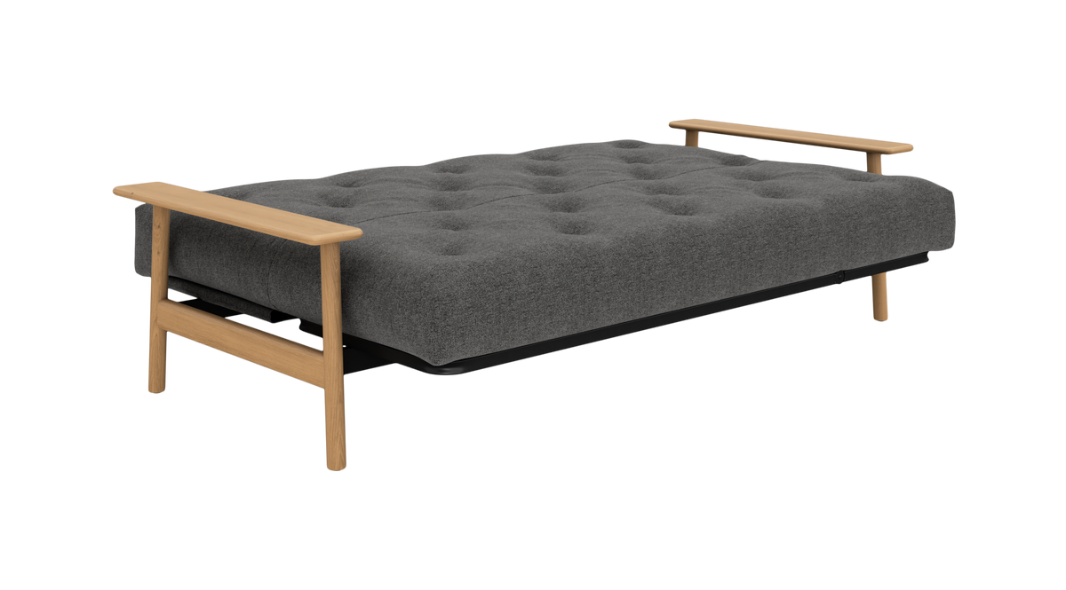 Grå, tuftet sovesofa med træarmlæn og synlige træben, frilagt på hvid baggrund.
