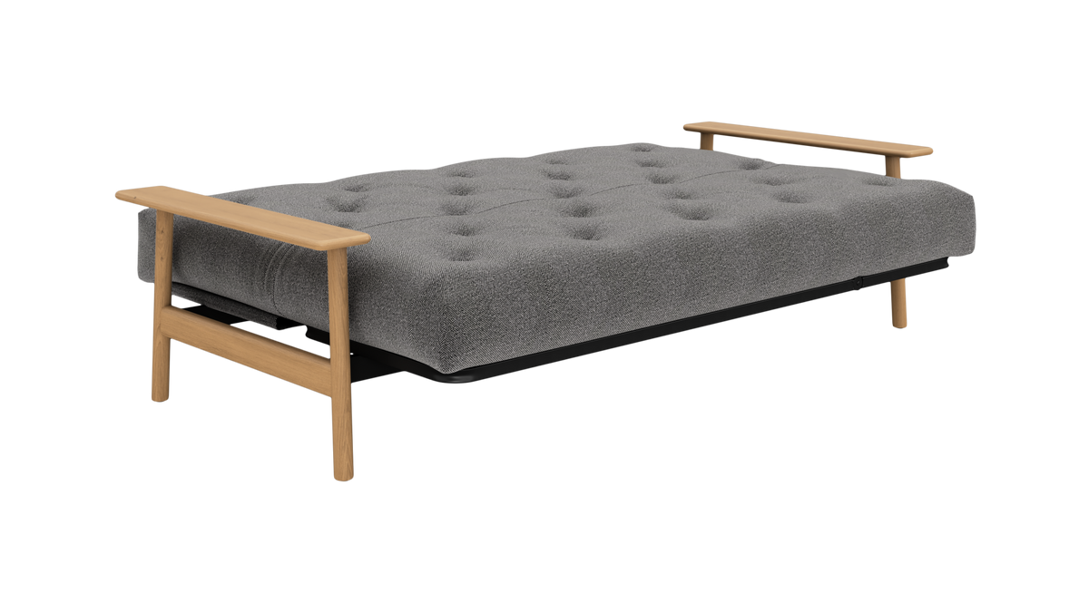 Grå knapquiltet sovesofa med lyse træarmlæn, frilagt produktbillede.