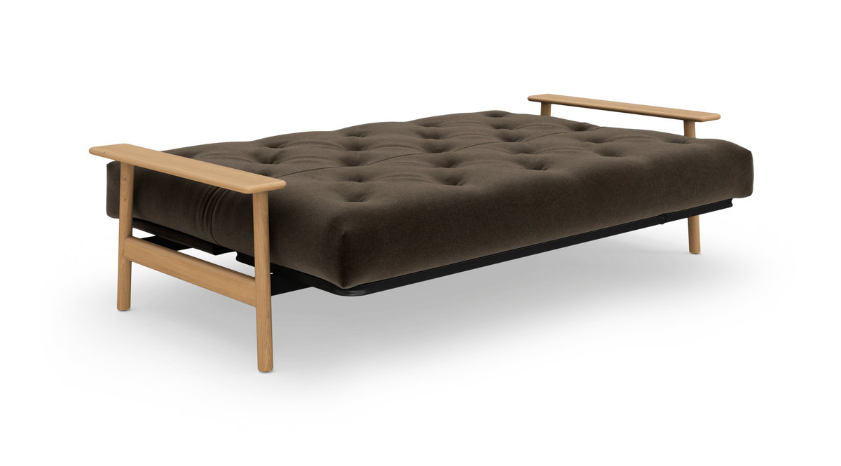 Brun, knapstukket sovesofa med lyse træarmlæn og ben, frilagt mod hvid baggrund i skrå frontvinkel.