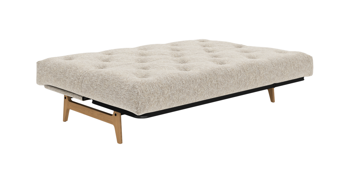 Beige sovesofa/daybed med tuftet madras og træben, frilagt på hvid baggrund.