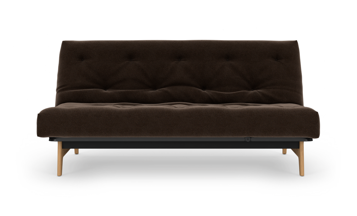 Mørkebrun, knapstikket sofa med træben set forfra på hvid studiebaggrund.