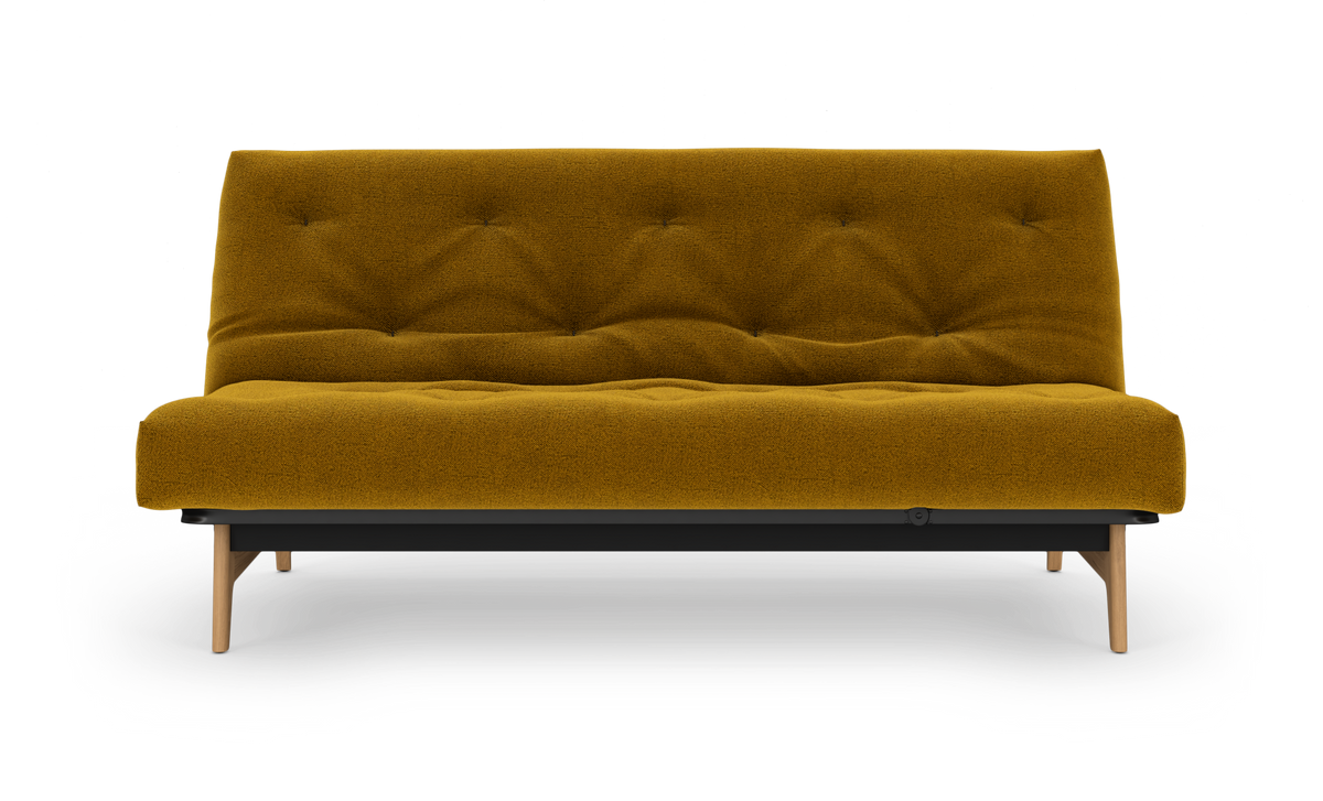 Sennepsgul sofa med træben set lige forfra på hvid baggrund.