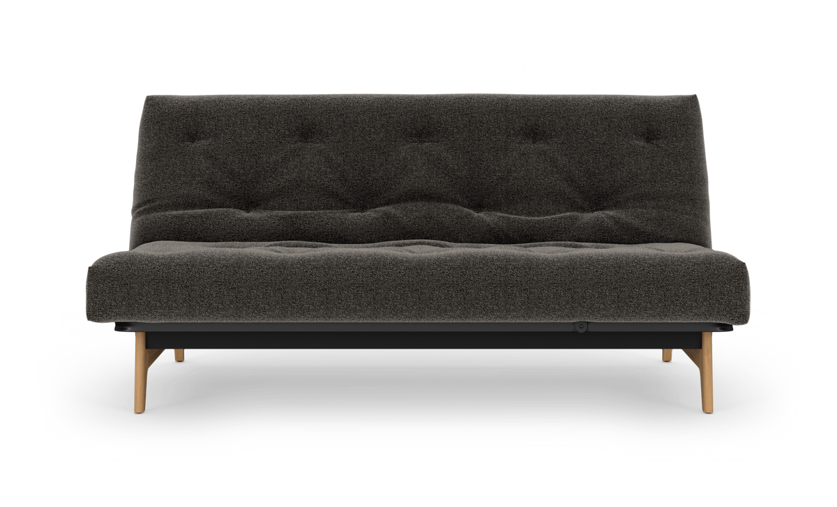 Mørkegrå, tuftet sofa/sovesofa med træben set forfra på hvid baggrund.