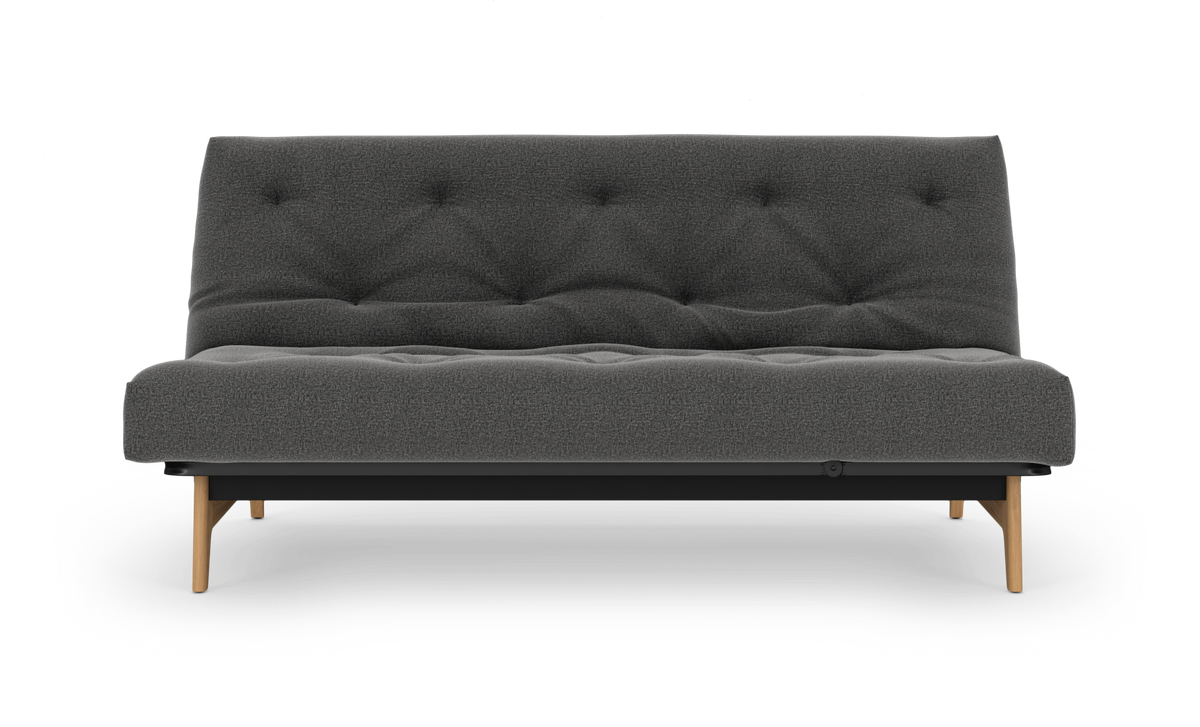 Mørkegrå, knappet sofa med træben på hvid baggrund.