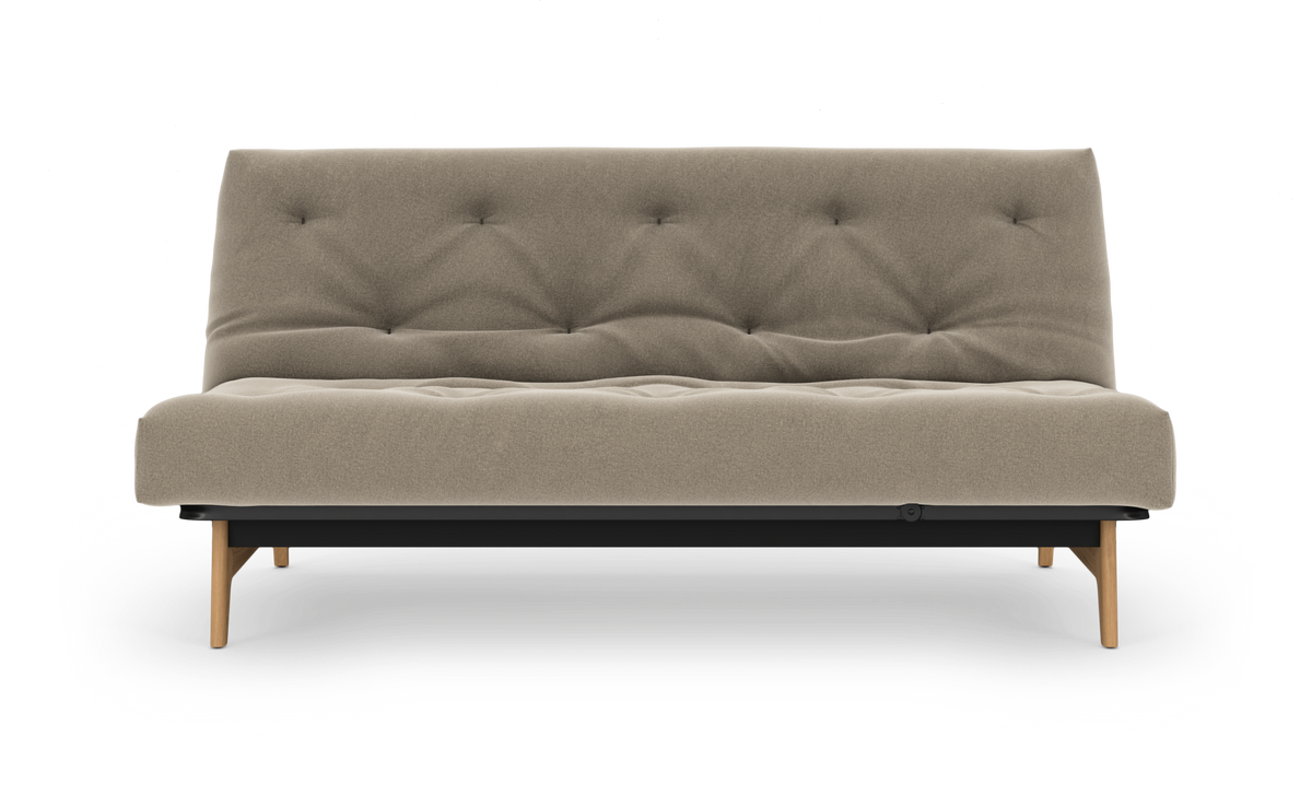 Beige, knappet sovesofa med træben fotograferet lige for mod hvid baggrund.