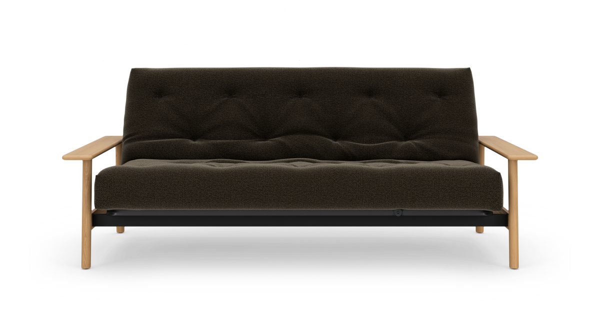 Mørkebrun, knap-quiltet sofa med lyse træarmlæn og ben set forfra mod hvid baggrund.